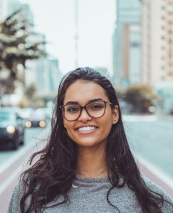 Woman with glasses smiling with the street in the background