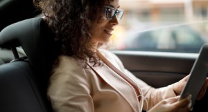 Woman in car with glasses reading from a tablet