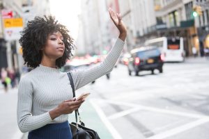 Woman hailing a cab or waiting for her ride share with a phone in her hand