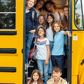 Ten children standing in opening of school bus door on the stairs