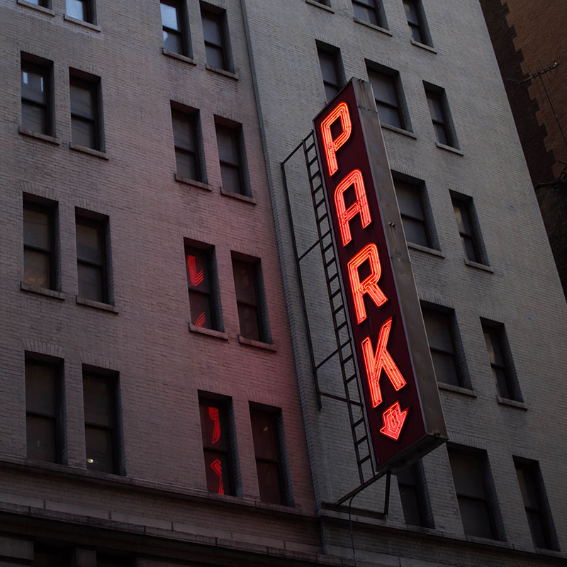 Parking sign on the side of a large city building.