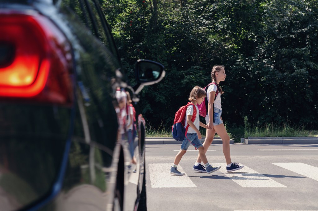 Two children crossing street at an intersection.