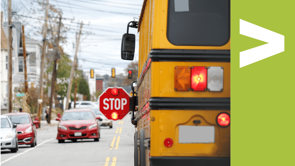 A stopped school bus on a city street with the safety stop arm sign extended to allow students to cross.
