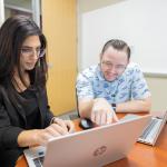 Two employees looking at laptop in an office