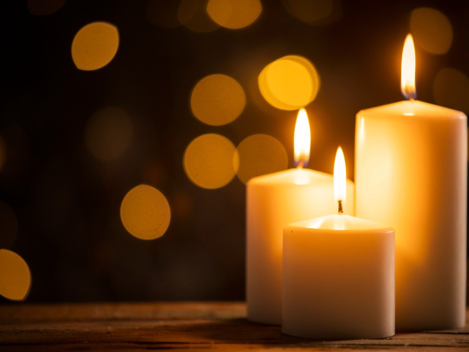 Close up of three burning candles on the wooden table