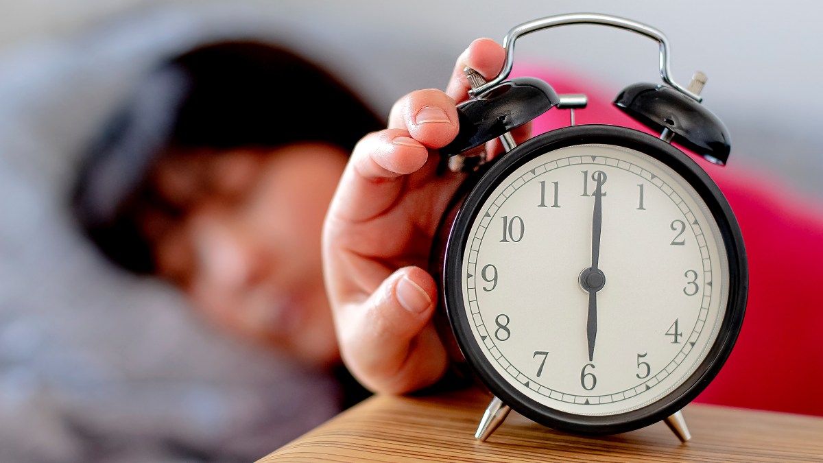 Sleepy man adjusting clock