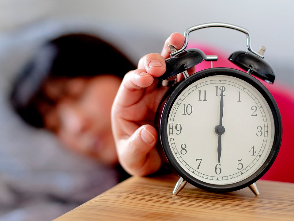 Sleepy man adjusting clock