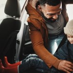 Father helping child with seat belt for safety traveling on vacation,