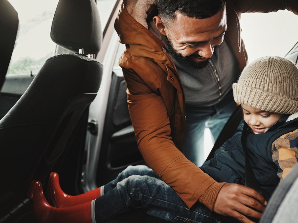Father helping child with seat belt for safety traveling on vacation,