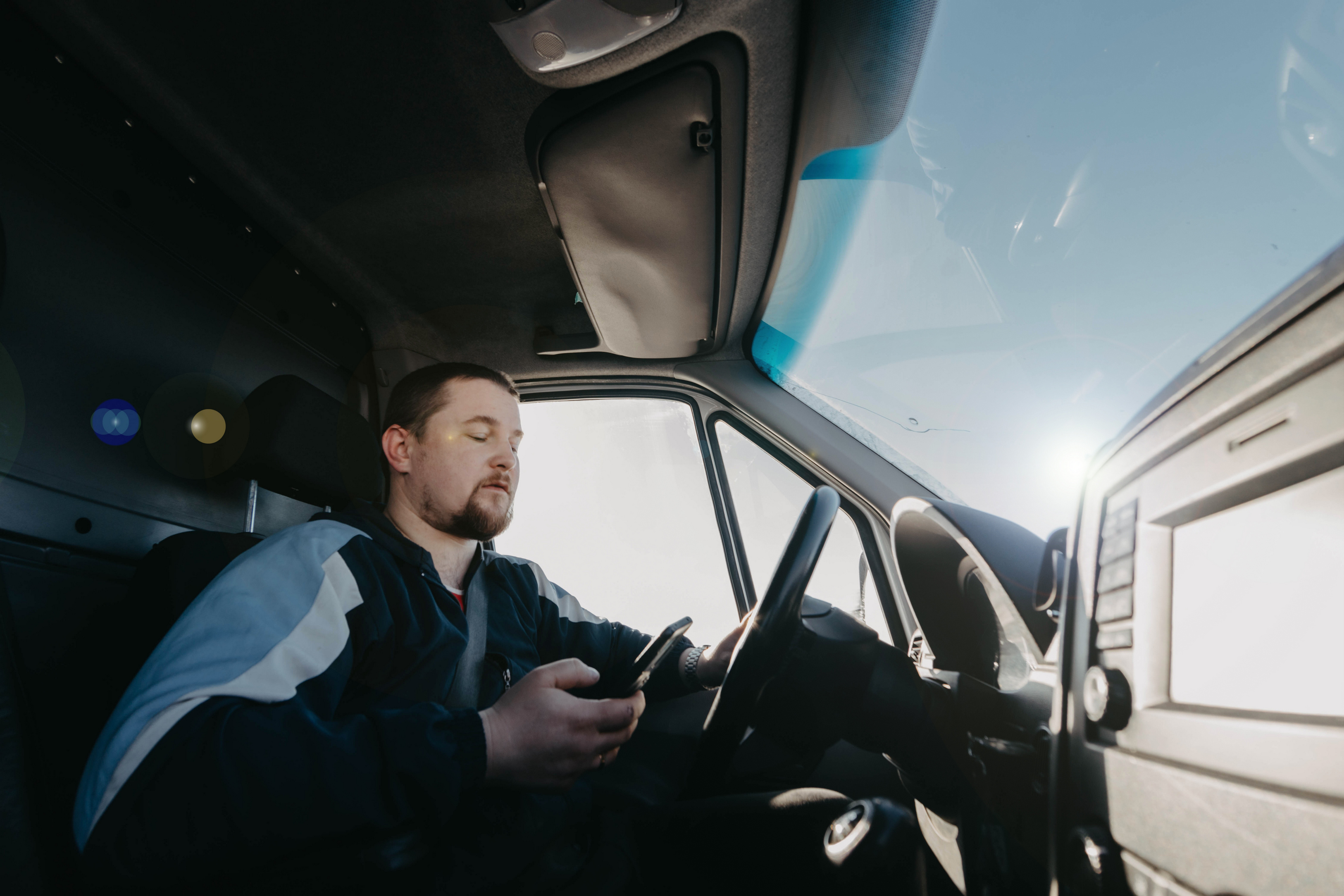 male truck driver with a smartphone in his hands is driving