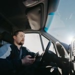 male truck driver with a smartphone in his hands is driving