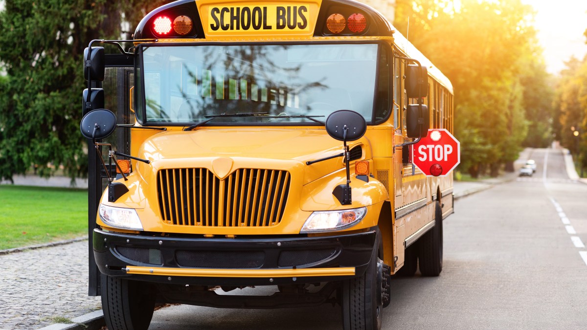 Old-fashioned yellow school bus with red stop sign on the side