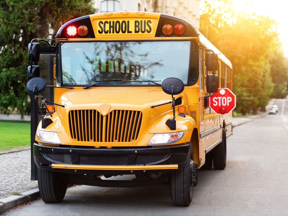 Old-fashioned yellow school bus with red stop sign on the side
