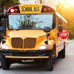 Old-fashioned yellow school bus with red stop sign on the side