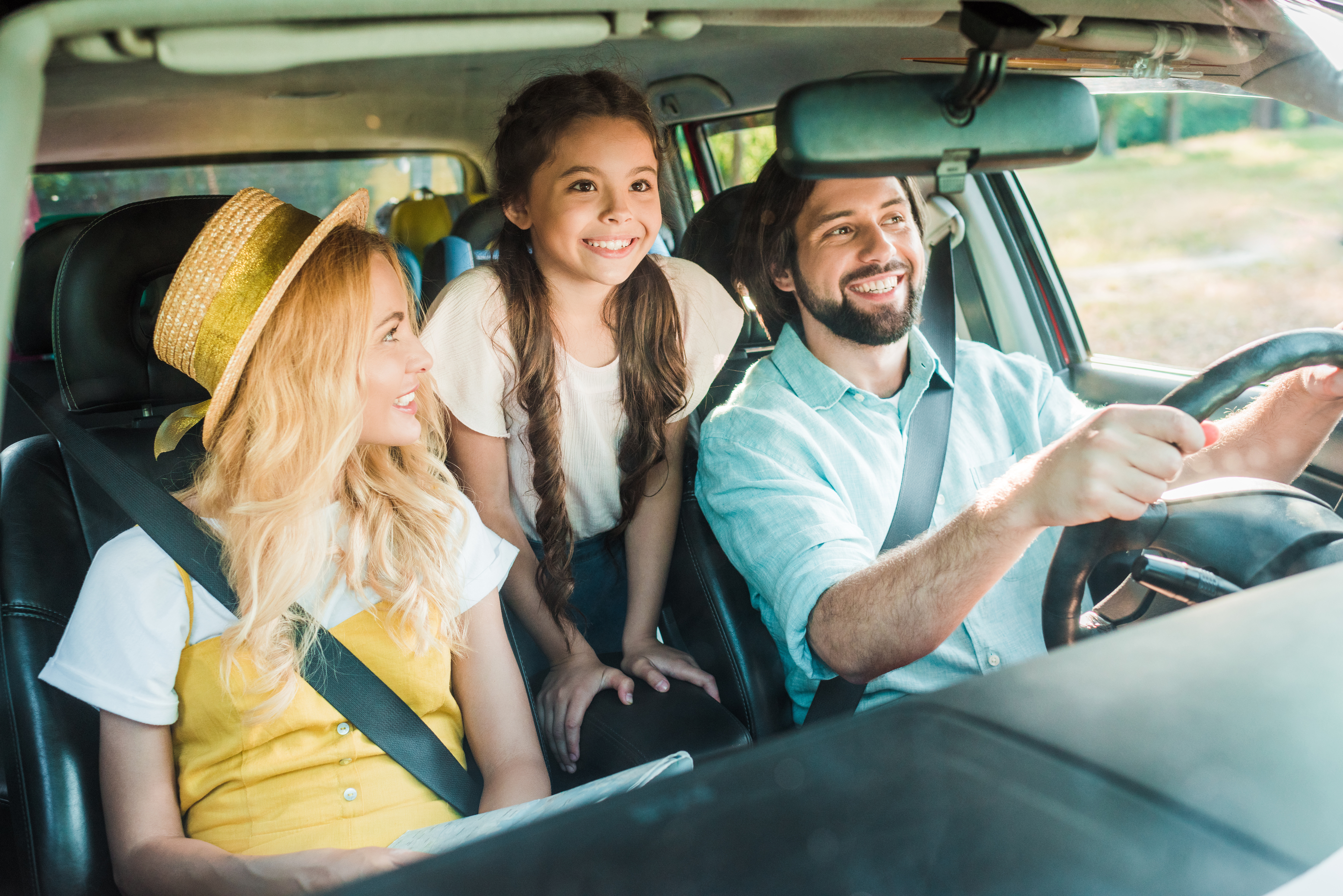 happy parents and daughter traveling by car
