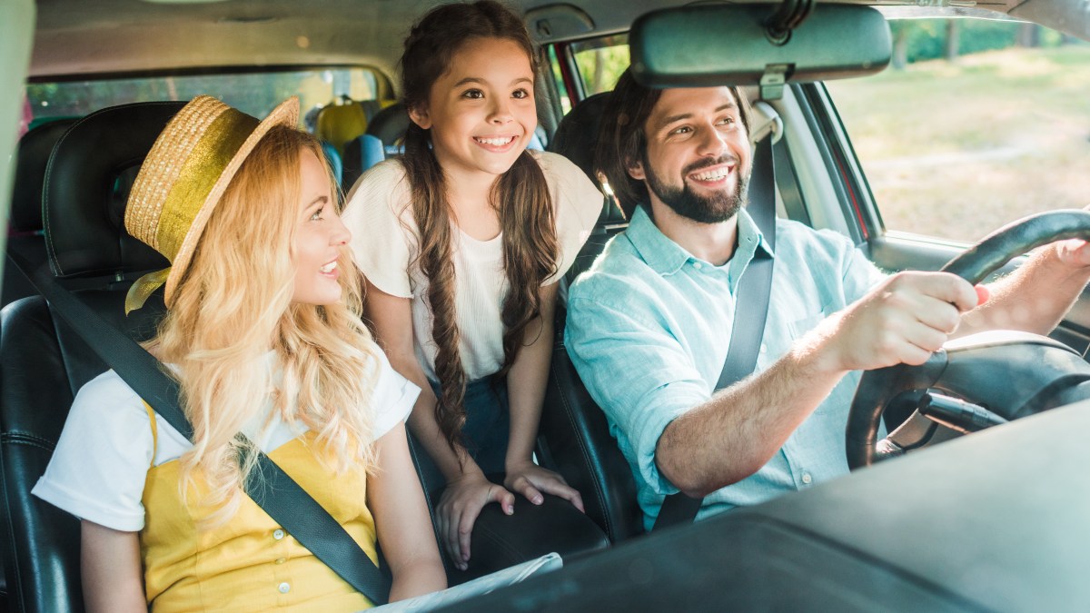 happy parents and daughter traveling by car