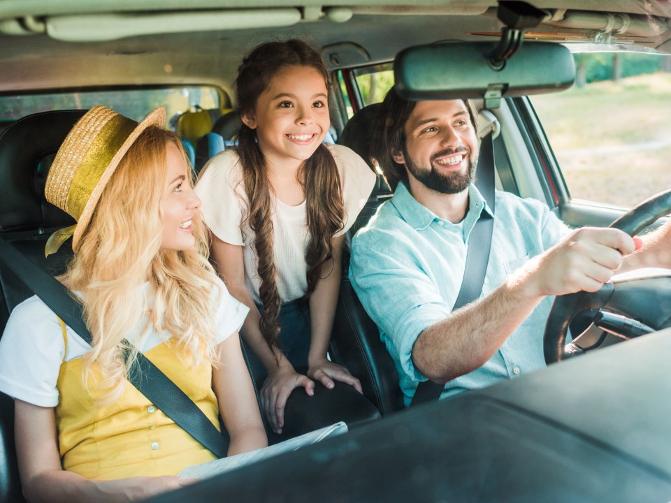 happy parents and daughter traveling by car