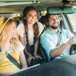 happy parents and daughter traveling by car
