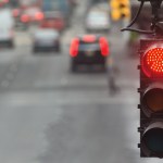Traffic light in the city with red signal on the background of the road