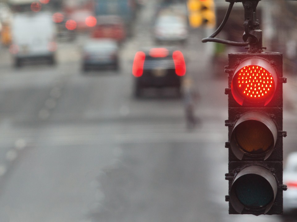 Traffic light in the city with red signal on the background of the road